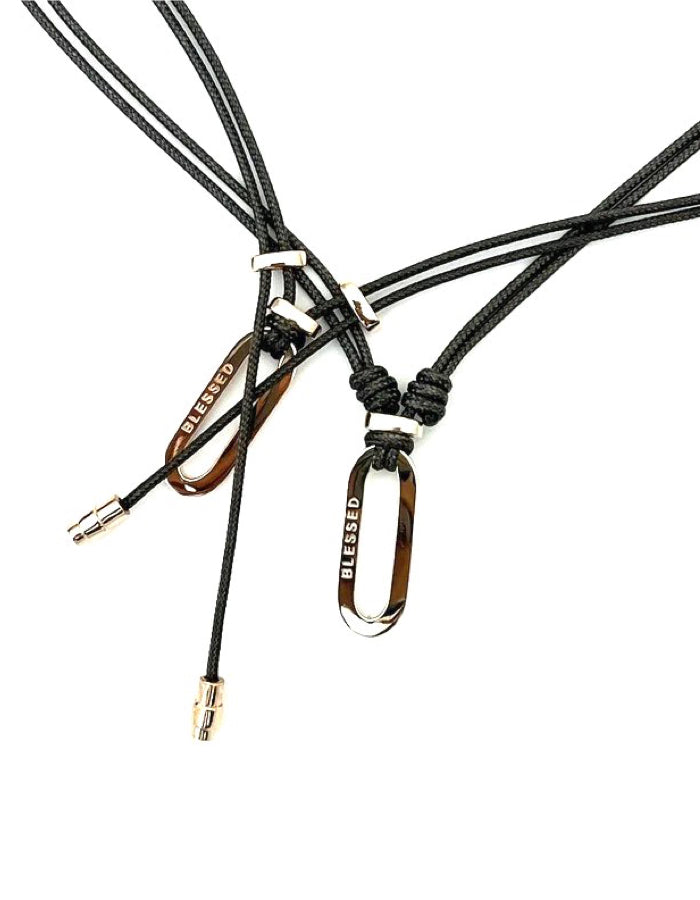 BLESSED Pendant—handcrafted in 18kt gold with "blessed" etched on an elegant oblong design. Draped on durable parachute cord, this unisex necklace blends luxury and meaning for everyday wear. Made in New York.