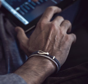 wrist of a man wearing a hook bracelet with a sterling silver ribbed cuff bracelet in sterling silver 