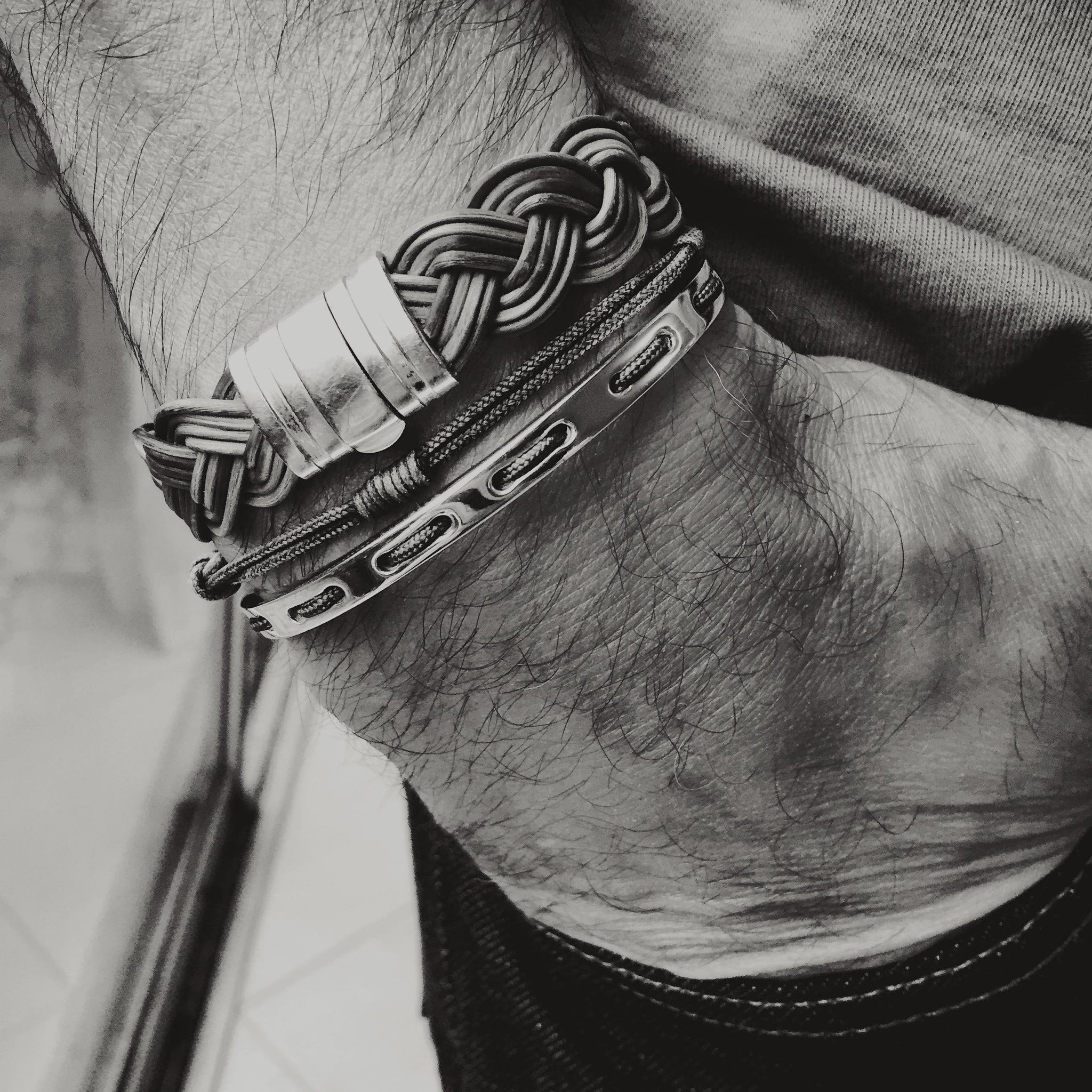 Wrist of a man wearing a stack of bracelets and a cuff handmade from buffalo horn, sterling silver and white gold.