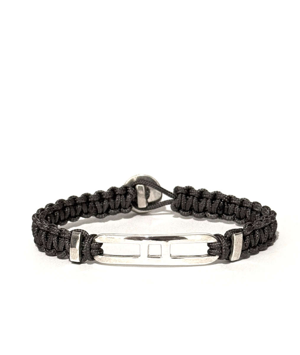 Grey braided bracelet with an open link and with silver clasp on a white background