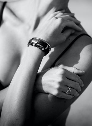 wrist of a woman wearing a buffalo horn bracelet with cord bracelets in precious gold.